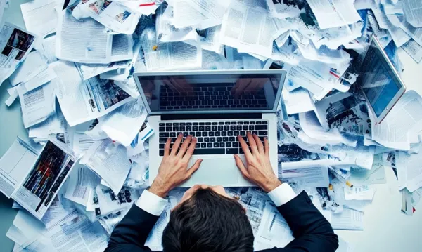 Ufficio con documenti cartacei e digitali in aumento, evidenziando la sfida della gestione documentale
